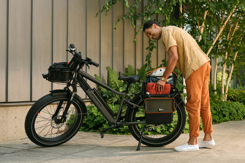 Man loading gear into the hardshell locking pannier on a Rad electric fat tire bike.