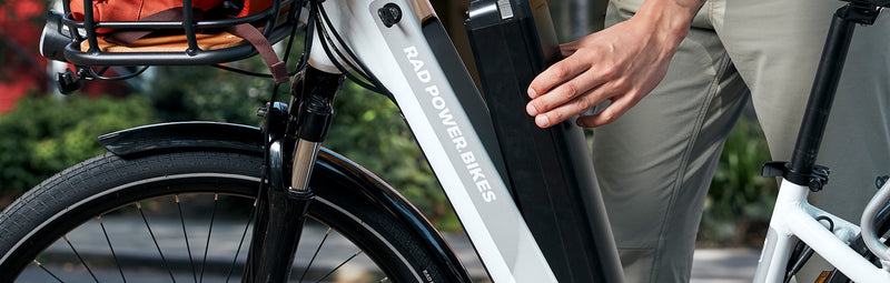 A man's hand removes a battery from his RadCity 5 Plus electric commuter bike.