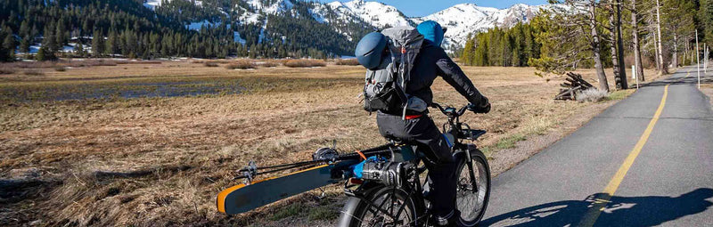 Individual rides on their ebike toward a snow-capped mountain.