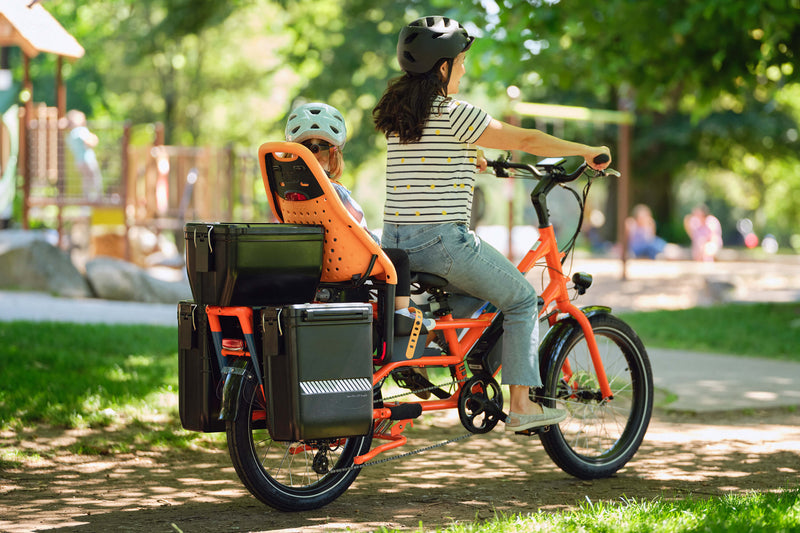 Woman and child on a RadWagon electric cargo bike with hardshell locking storage accessories mounted to the back.