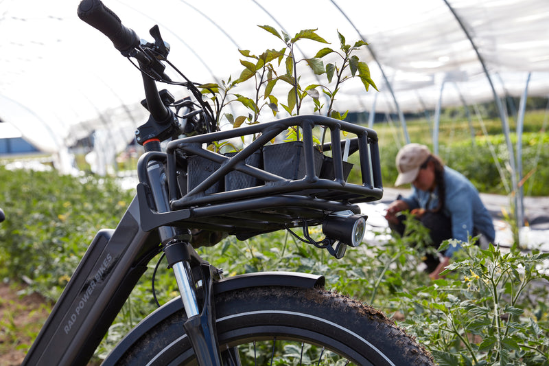 Close up of an electric bike in a greenhouse with a farmer in the background.