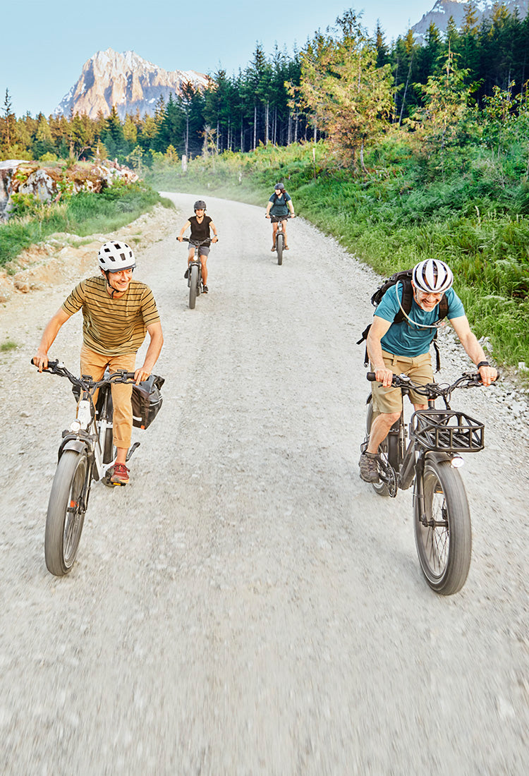 Group of people riding electric bikes on a dirt road.