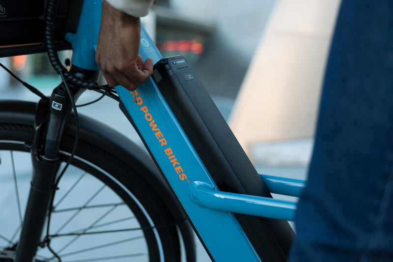 Person managing the key for a Safe Shield Advanced Semi-Integrated battery installed on a blue Radster Road electric commuter bike